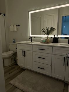 a bathroom with white cabinets and a large mirror