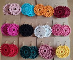 there are many crocheted earrings on the table with each one being sold off