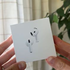 a person holding an apple airpods in their left hand, with the box open