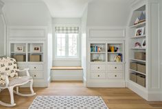 a room with white walls and wooden floors, built - in bookshelves on the far wall