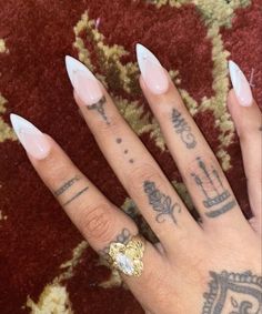 a person with tattoos on their fingers and nails, wearing a gold plated ring