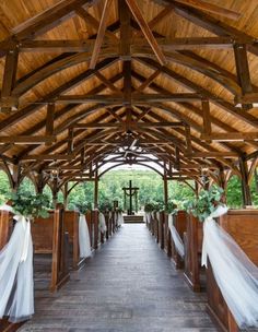 the inside of a church with wooden pews and white organels on them, decorated with greenery