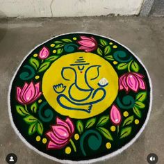 a colorful painting on the ground in front of a white wall with a yellow ganeshi