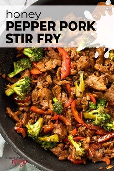 beef and broccoli stir frying in a skillet with a wooden spoon