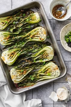 roasted artichokes on a baking sheet with garlic and seasoning in bowls