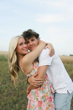 two people hugging each other in a field