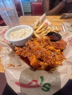 chicken wings, macaroni and cheese on a paper wrapper with dipping sauce