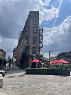 two red umbrellas sitting on the side of a road next to a tall building