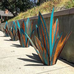 three metal planters sitting on the side of a road next to a cement wall