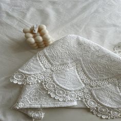 an image of white lace and beads on a bed sheet with the sheets folded down