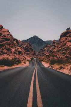 an empty road in the middle of some mountains