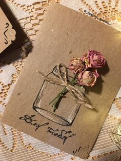 some flowers are sitting in a glass jar on a lace doily with twine