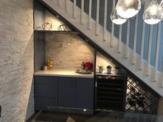 a wine rack under the stairs in a home bar with lights hanging from it's ceiling