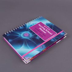 a spiral notebook with the words workbook written in pink and blue, on a grey surface