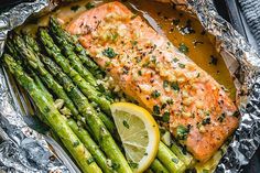 salmon and asparagus in foil with lemon wedges on the side for garnish