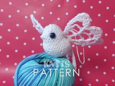 a crocheted ball of yarn with a white and blue bird sitting on top