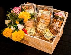 a wooden box filled with lots of different types of food and flowers on top of a table