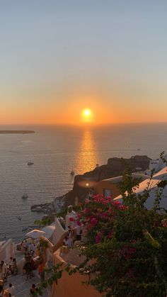 the sun is setting over an ocean with boats in the water and people sitting at tables under umbrellas