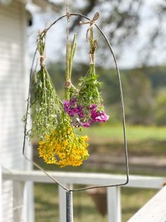 some flowers hanging from a metal stand on a porch