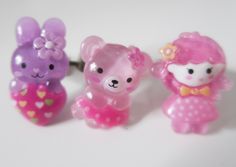 three little teddy bears in pink, purple and green colors with hearts on them sitting next to each other