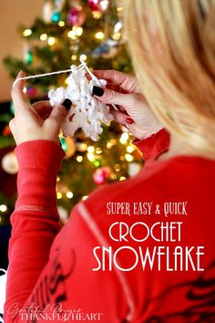 a woman is decorating a christmas tree with crochet snowflakes