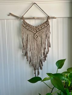 a wall hanging made out of wood sticks and rope with tassels on it