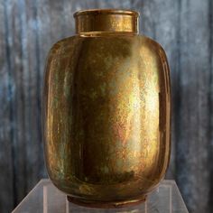 a gold vase sitting on top of a clear shelf