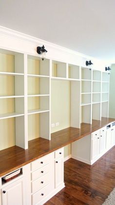 an empty room with white bookcases and wooden floors