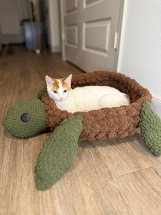 a cat laying in a turtle bed on the floor