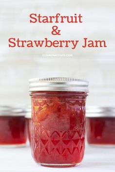 a jar filled with strawberry jam sitting on top of a white table next to other jars