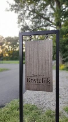 a wooden sign sitting on the side of a road next to a grass covered field