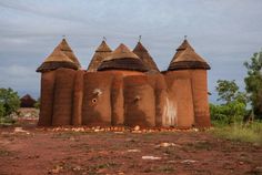 a group of mud huts sitting on top of a dirt field