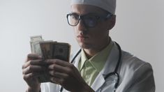 a male doctor in a white coat is holding money