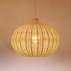 a rattan light hanging from a ceiling in a room with beige walls and flooring