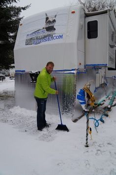 a man is shoveling snow in front of an rv