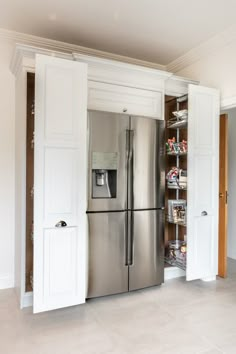 a stainless steel refrigerator and freezer combo in a kitchen with white cabinet doors open