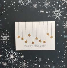 a new year card with gold stars hanging from strings and snowflakes in the background