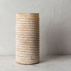 a white vase sitting on top of a table next to a gray wall and floor