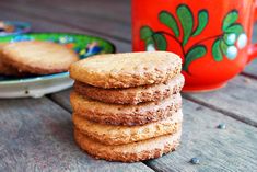 a stack of cookies sitting on top of a wooden table next to a red mug