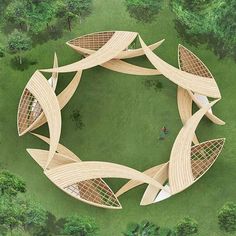 an aerial view of a circular wooden structure in the middle of a green field surrounded by trees