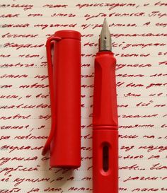 two red pens sitting next to each other on top of a paper