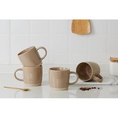 three coffee mugs sitting on top of a counter next to spoons and measuring cups