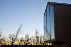 a building that has some trees in front of it with the sun setting behind it