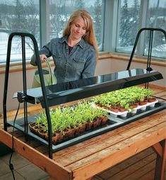 a woman standing in front of a table filled with plants