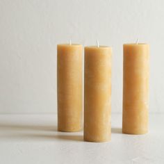 three candles sitting next to each other on top of a white tablecloth covered floor