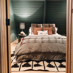 a large bed sitting inside of a bedroom next to a wooden door with two lamps on each side