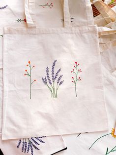 three embroidered bags sitting on top of each other next to some scissors and yarns