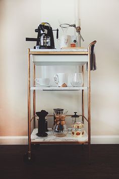 a shelf with coffee cups and other items on it in front of a white wall