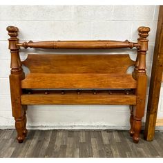 an old wooden bed frame with two posts on the top and bottom, against a white brick wall