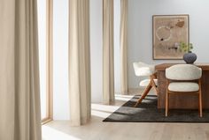 a dining room table with two chairs and a painting on the wall behind it in front of curtains